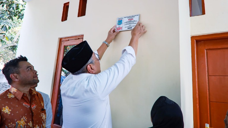 Walikota Tangsel Benyamin Davnie memasang nomor rumah hasil bedah ruma. (Foto l: Dok Pemkot)